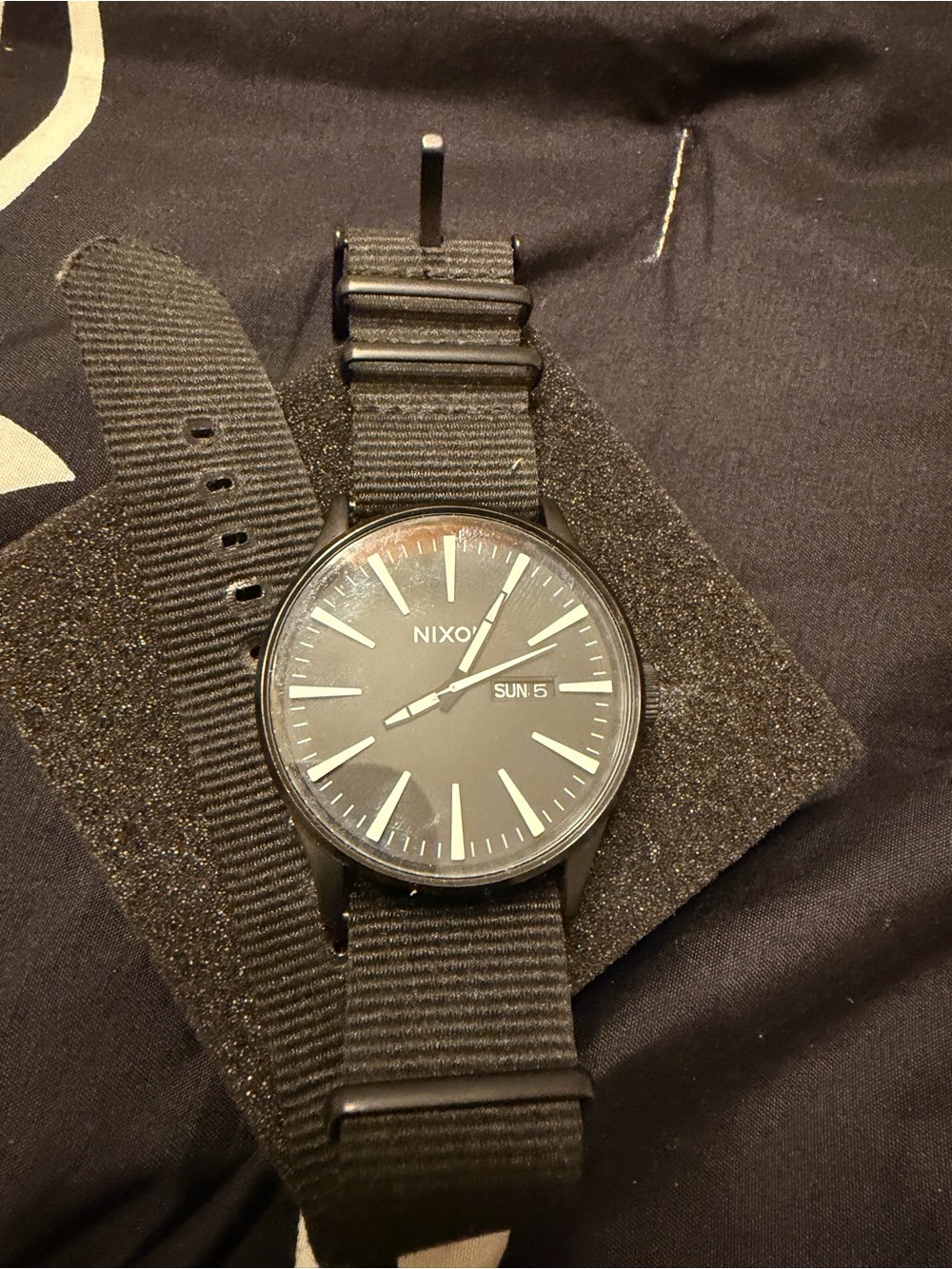 Nixon All-Black Nylon Strap Watch with Day Window

Needs a battery
